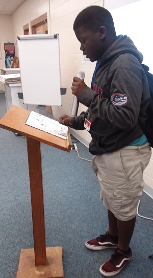 Middle school student reading a poem into a microphone. 